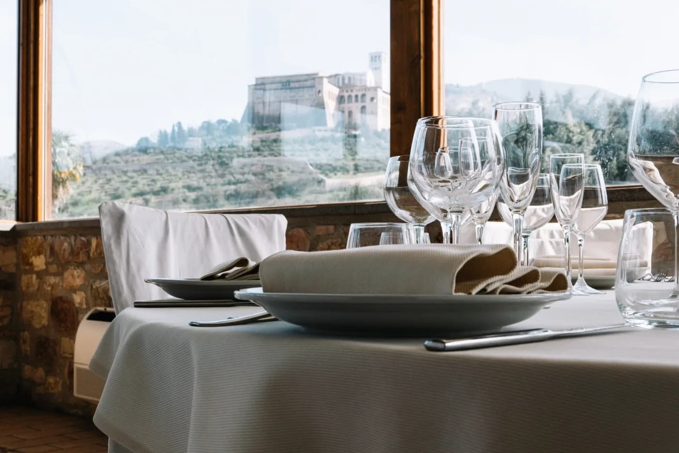 Gedeckter Tisch am Fenster, im Hintergrund der Sacro Convento von Assisi