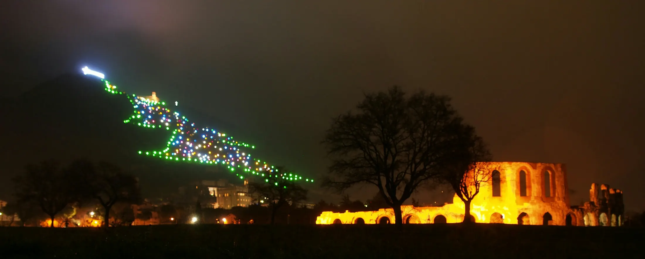 L'albero di Natale di Gubbio illuminato di notte sulle pendici del Monte Ingino, sopra le mura della città