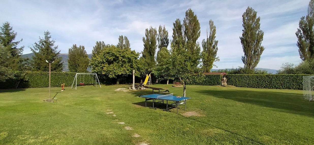 The playground at Agriturismo La Mora: swings, a yellow slide, a table-tennis table and a football goal on the lawn
