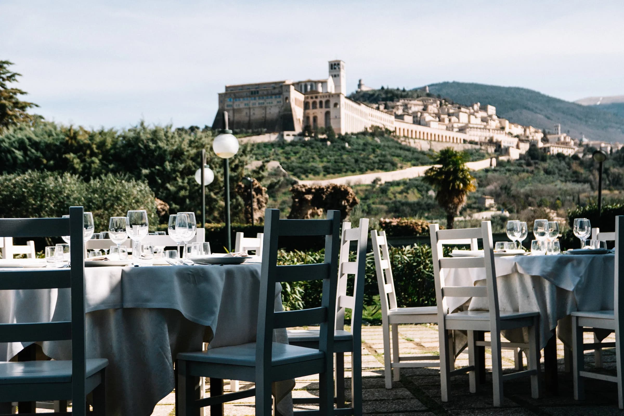 Terrasse des Ristorante Carfagna mit gedeckten Tischen und der Basilika des Heiligen Franziskus im Hintergrund, Assisi
